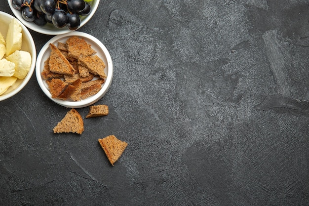 Draufsicht frische trauben mit weißem käse und geschnittenem dunklem brot auf dunkler oberfläche mahlzeit frühstücksgericht milchfrucht