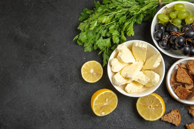 Draufsicht frische trauben mit weißem käsegrün und zitronenscheiben auf dunkler oberfläche mahlzeit frühstücksgericht milchfrucht