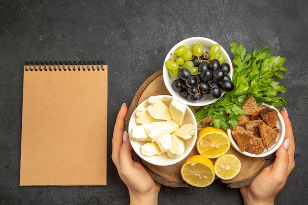 Draufsicht frische trauben mit weißen käsezitronenscheiben und grüns auf der dunklen oberfläche essen mahlzeit milchfrucht