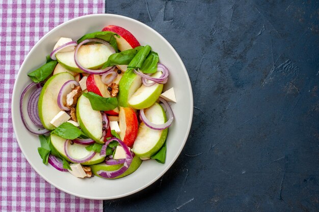 Draufsicht frischer Apfelsalat in Schüssel lila und weiß karierte Tischdecke auf dunklem Tischfreiraum