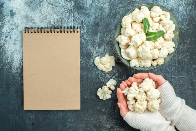 Draufsicht frischer Blumenkohl Innenteller in weiblichen Händen auf dem hellgrauen Tisch