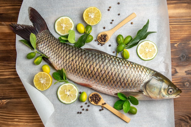 Draufsicht frischer Fisch mit Zitronenscheiben auf Holztischnahrung Meeresfrüchtegericht Ozean