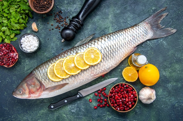 Draufsicht frischer Fisch mit Zitronenscheiben Messer Granatapfelkerne Schüssel auf Küchentisch