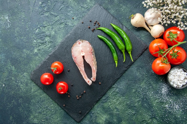 Draufsicht frischer Fisch Scheibe mit Tomaten und grünem Pfeffer auf dunklem Hintergrund Meeresfrüchte Ozeanfleisch Meeresmehl Wasser Pfeffer Pfeffer Gericht Essen