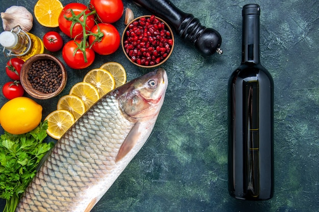 Draufsicht frischer Fisch Tomaten Pfeffermühle Zitronenscheiben Weinflasche auf Küchentisch