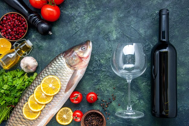 Draufsicht frischer Fisch Zitronenscheiben Granatapfelkerne Schüssel Weinflasche und Glas auf Tisch Freiraum