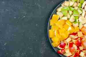 Kostenloses Foto draufsicht frischer obstsalat in scheiben geschnittene bananen, äpfel und orangen auf dunklem hintergrund