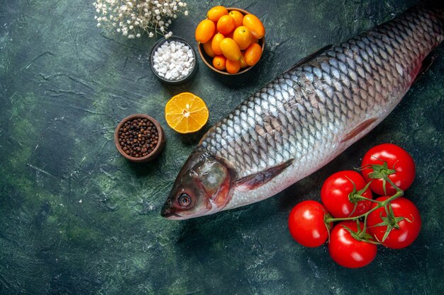 Draufsicht frischer roher Fisch mit roten Tomaten auf dunklem Hintergrund