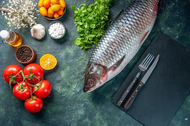Draufsicht frischer roher Fisch mit Tomaten und Grüns auf dunklem Hintergrund