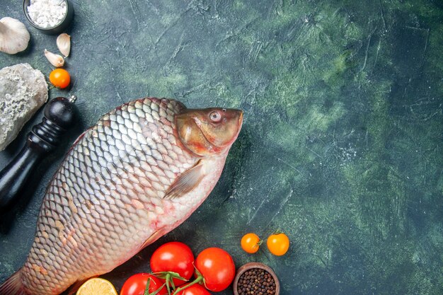 Draufsicht frischer roher Fisch mit Tomaten und Pilzen auf dunkelblauem Hintergrund