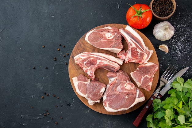 Draufsicht frisches Fleisch schneidet rohes Fleisch mit Grüns und Tomaten auf dunkler Küche Mahlzeit Essen Kuh Essen Teller Salat Tier