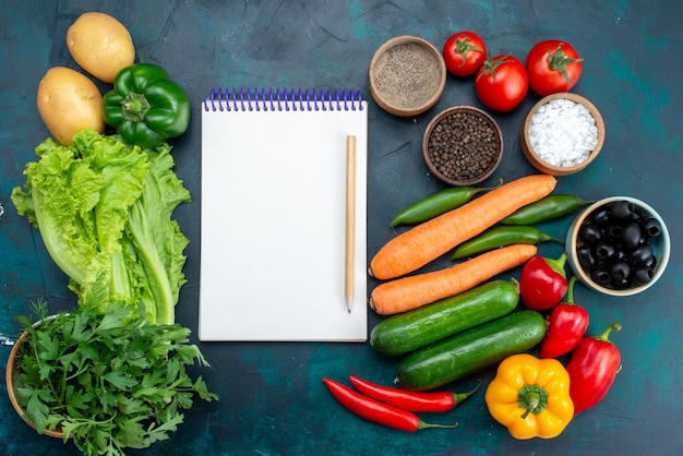 Draufsicht frisches Gemüse mit Gemüse und Notizblock auf dem dunkelblauen Schreibtisch Mittagssalat Snack Gemüselebensmittel