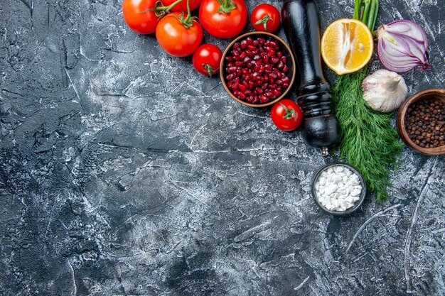 Draufsicht frisches Gemüse Schalen mit Granatapfelkernen Meersalz schwarzer Pfeffer Zwiebel Knoblauch Dill auf grauem Hintergrund Kopie Raum