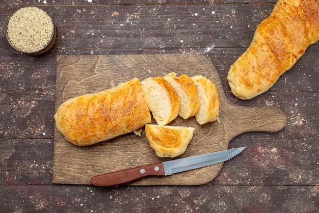 Kostenloses Foto draufsicht frisches leckeres gebäck langes brötchen gebildet geschnittenes gebäck auf dem braunen hölzernen schreibtischbrötchengebäck-teigbrotmehl