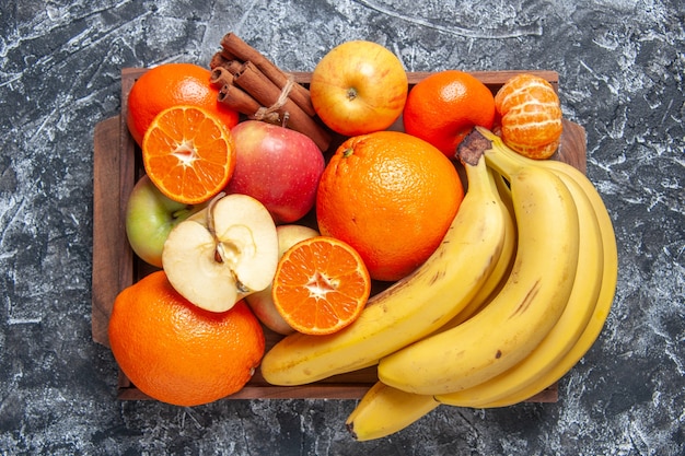 Draufsicht frisches Obst Bananen Äpfel Orangen Zimtstangen auf Holztablett auf dem Tisch