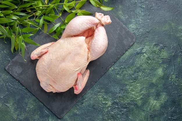 Draufsicht frisches rohes Huhn mit grünen Blättern auf dunklem Hintergrund Hühnermehl Tierfoto Lebensmittelfarbe Küchenfleisch