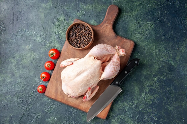 Draufsicht frisches rohes Huhn mit roten Tomaten auf dunkelblauem Hintergrund Küche Mahlzeit Tierfoto Essen Hühnerfleisch Farbe Bauernhof