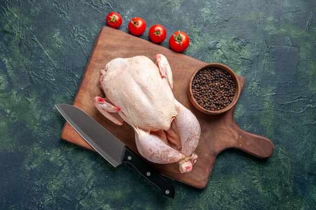 Draufsicht frisches rohes Huhn mit roten Tomaten auf dunkelblauem Hintergrund Küche Mahlzeit Tierfoto Essen Hühnerfleisch Farbe Bauernhof