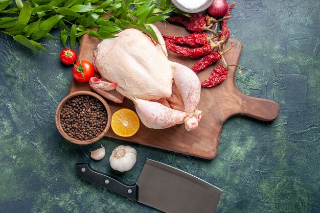 Draufsicht frisches rohes Huhn mit roten Tomaten auf dunkelblauem Hintergrund Küchenmahlzeit Tierfotofutter Hühnerfleischfarbe