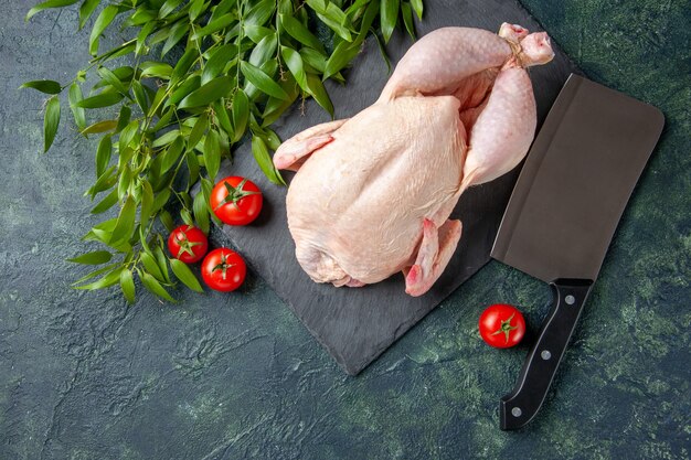 Draufsicht frisches rohes Huhn mit roten Tomaten auf dunklem Hintergrund Hühnermehl Tierfoto Lebensmittelfarbe Küchenfleisch