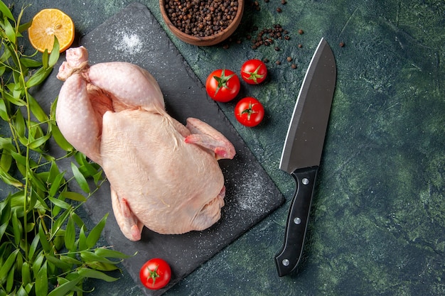 Draufsicht frisches rohes huhn mit roten tomaten auf dunklem hintergrund mahlzeit tierfoto lebensmittelfarbe hühnerfleisch