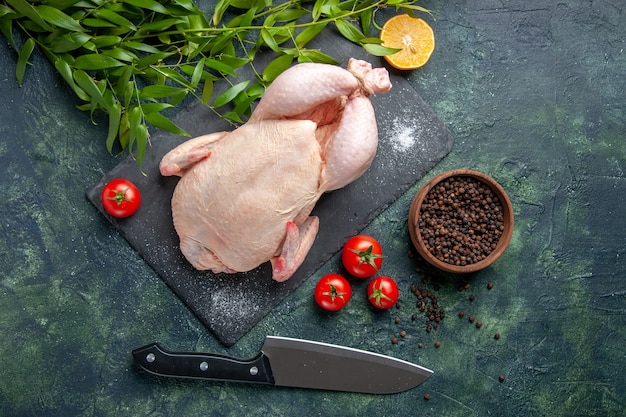 Draufsicht frisches rohes Huhn mit roten Tomaten auf dunklem Hintergrund Mahlzeit Tierfoto Lebensmittelfarbe Huhn Küche