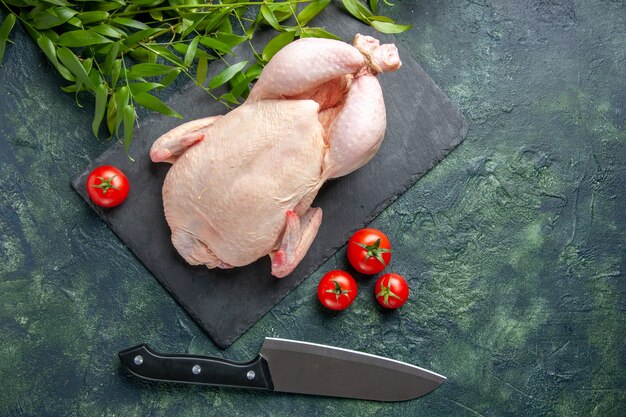 Draufsicht frisches rohes Huhn mit roten Tomaten auf dunklem Hintergrund Mahlzeit Tierfoto Lebensmittelfarbe Huhn Küchenfleisch