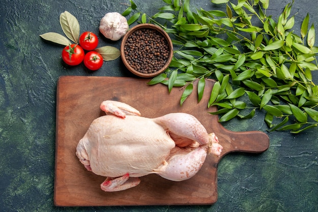 Draufsicht frisches rohes huhn mit tomaten auf dunkelblauem hintergrund küche restaurant mahlzeit tierfoto bauernhof farbe lebensmittel hühnerfleisch