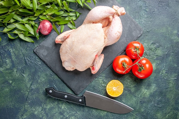Draufsicht frisches rohes Huhn mit Tomaten auf dunklem Hintergrund Mahlzeit Tierfoto Essen Huhn Küche Fleischfarbe