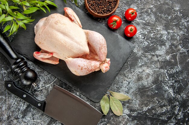 Draufsicht frisches rohes Huhn mit Tomaten auf hell-dunklem Hintergrund Küche Mahlzeit Tierfoto Hühnerfleisch Farbe Bauernhof