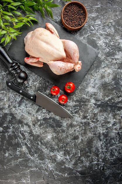 Draufsicht frisches rohes Huhn mit Tomaten auf hellem dunklem Hintergrund Küchenmahlzeit Tierfoto Hühnerfleischfarbe Bauernhoflebensmittel