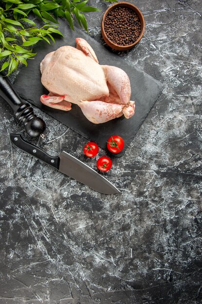 Draufsicht frisches rohes Huhn mit Tomaten auf hellem dunklem Hintergrund Küchenmahlzeit Tierfoto Hühnerfleischfarbe Bauernhoflebensmittel