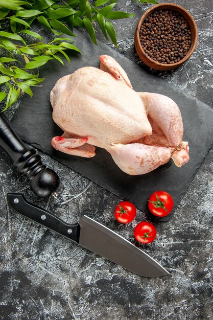 Draufsicht frisches rohes Huhn mit Tomaten auf hellem dunklem Hintergrund Küchenmahlzeit Tierfoto Hühnerfleischfarbe Bauernhoflebensmittel