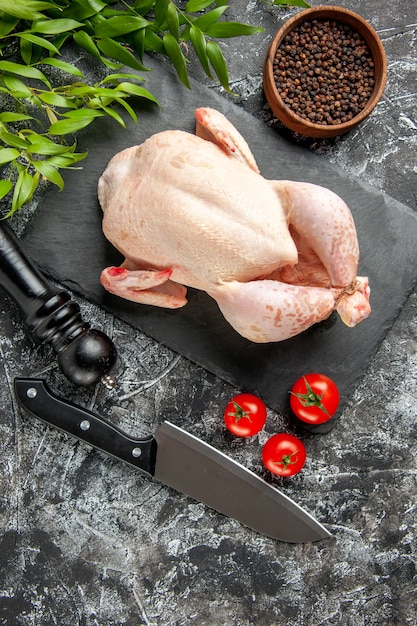 Draufsicht frisches rohes Huhn mit Tomaten auf hellem dunklem Hintergrund Küchenmahlzeit Tierfoto Hühnerfleischfarbe Bauernhoflebensmittel