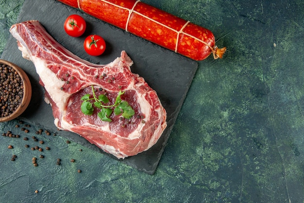 Draufsicht Frischfleischscheibe mit Pfeffer und Wurst auf dunkelblauem Hintergrund Küche Tier Kuh Huhn Lebensmittelfarbe Metzgerfleisch