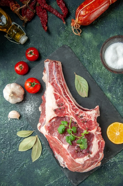 Draufsicht Frischfleischscheibe mit roten Tomaten auf dunkelblauem Hintergrund Küche Tier Kuh Essen Metzger Fleisch Hühnerfarbe