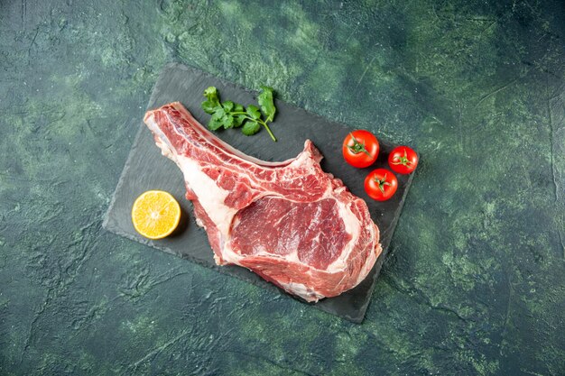 Draufsicht Frischfleischscheibe mit roten Tomaten auf dunkelblauem Hintergrund Küche Tier Kuh Essen Metzger Fleischfarbe