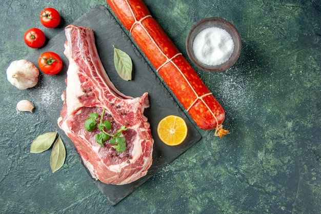 Draufsicht Frischfleischscheibe mit Tomaten und Wurst auf dunkelblauem Hintergrund Küche Tier Kuh Lebensmittelfarbe Metzger Fleisch Huhn