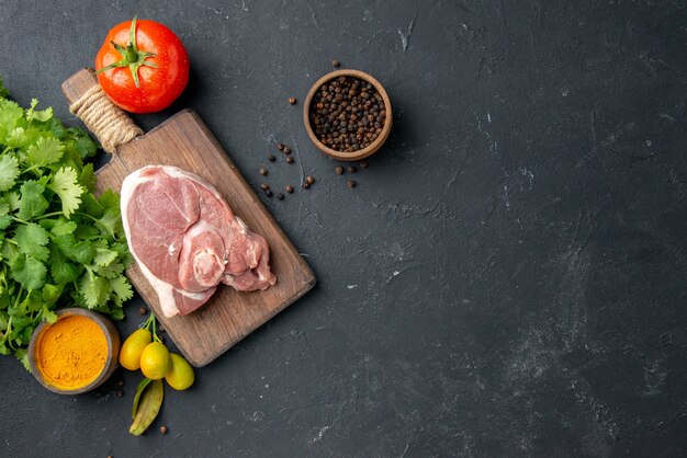 Draufsicht Frischfleischscheibe rohes Fleisch mit Grüns auf dunklem Grillgericht Pfeffer Küche Essen Kuh Essen Salat Tiermehl