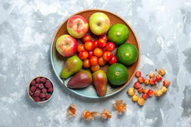 Draufsicht Fruchtzusammensetzung Äpfel Birnen Mandarinen und Pflaumen auf weißem Schreibtisch.