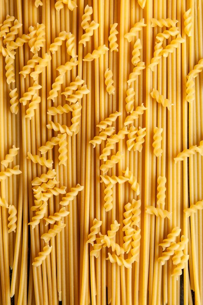 Draufsicht-Fusilli-Makkaroni-Nudeln mit Spaghetti auf Hintergrund. Vertikale