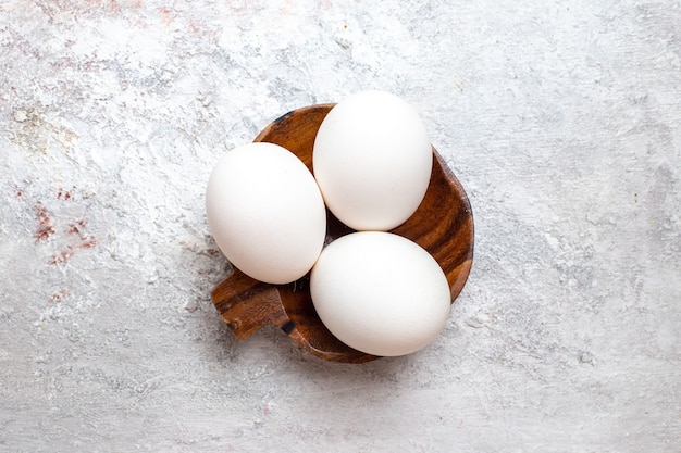 Draufsicht ganze rohe Eier auf roher Frühstücksmahlzeitnahrung der weißen Oberfläche Ei