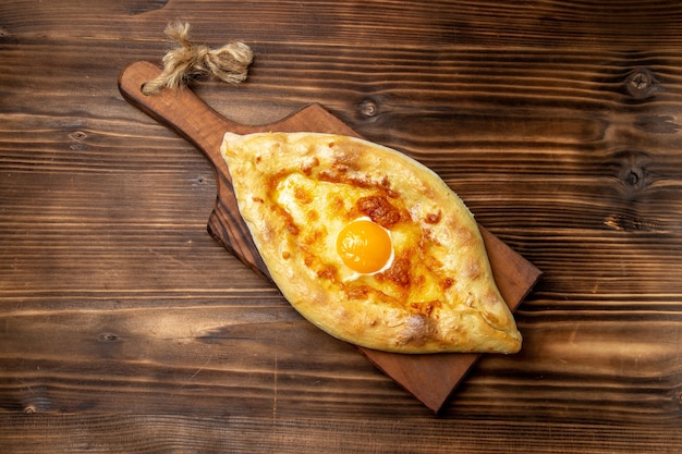 Draufsicht gebackenes Brot mit gekochtem Ei auf dem hölzernen Schreibtischbrotteigbrötchen-Nahrungsmittelfrühstück