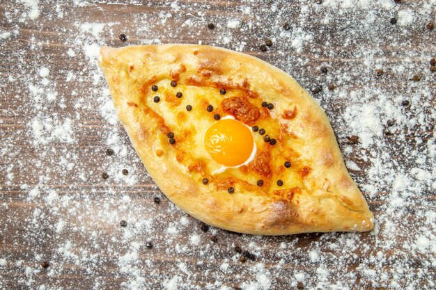 Draufsicht gebackenes Brot mit gekochtem Ei und Mehl auf dem braunen Oberflächenteig backen Eierbrötchen