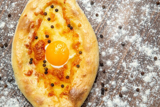 Draufsicht gebackenes Brot mit gekochtem Ei und Mehl auf der braunen Oberfläche Teig Eierbrötchen Frühstück