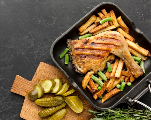 Draufsicht gebackenes Huhn und Kartoffeln in der Pfanne mit Gurken