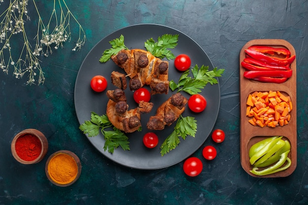 Draufsicht gebratene Fleischscheiben mit Gemüse und Gewürzen auf der dunkelblauen Oberfläche Gemüsemehl Lebensmittel Fleisch Abendessen Gesundheit