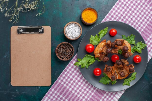 Draufsicht gebratene Fleischscheiben mit grünem Notizblock und Kirschtomaten auf der dunklen Oberfläche Fleischnahrungsmittelmahlzeit-Gemüsebraten