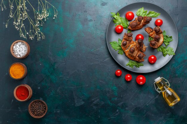 Draufsicht gebratene Fleischscheiben mit Olivenöl und Gewürzen auf der dunkelblauen Schreibtischgemüsemahlzeit-Fleischmahlzeit