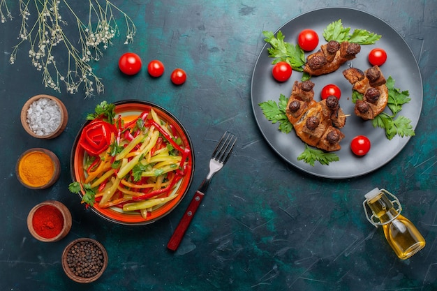 Draufsicht gebratene Fleischscheiben mit Olivenölsalat und Gewürzen auf dunkelblauer Schreibtischgemüse-Fleischgesundheitsmahlzeit